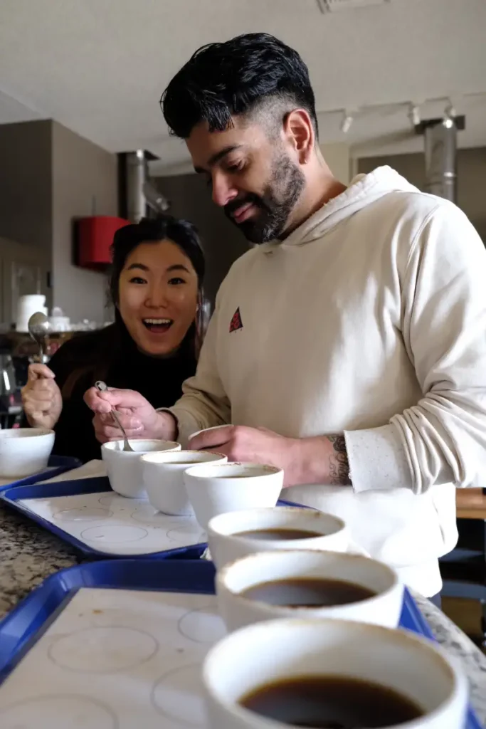 a man and woman smiling while cupping coffee